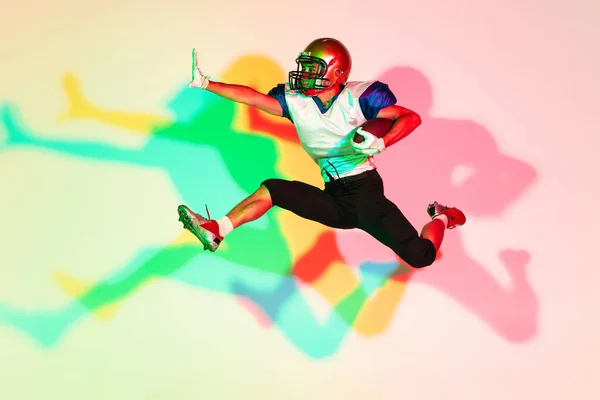 Jogador de futebol americano isolado no fundo do estúdio gradiente em luz de néon com sombras — Fotografia de Stock