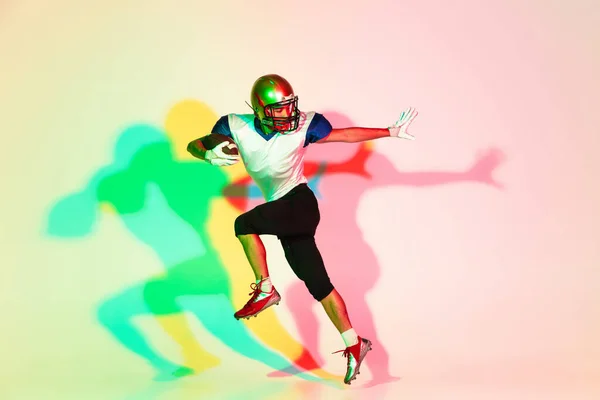 American football speler geïsoleerd op gradiënt studio achtergrond in neon licht met schaduwen — Stockfoto