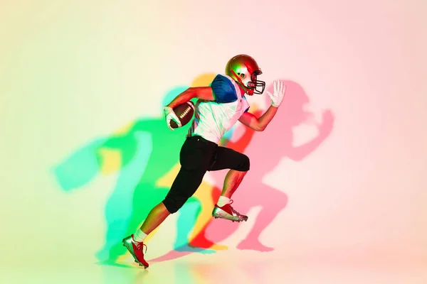 American football speler geïsoleerd op gradiënt studio achtergrond in neon licht met schaduwen — Stockfoto