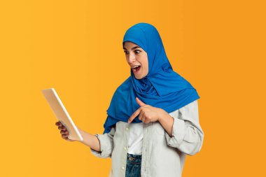 Sarı stüdyo arka planında izole edilmiş genç Müslüman kadın portresi