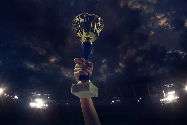 Prix de la victoire, mains masculines serrant la coupe des gagnants contre ciel sombre nuageux — Photo