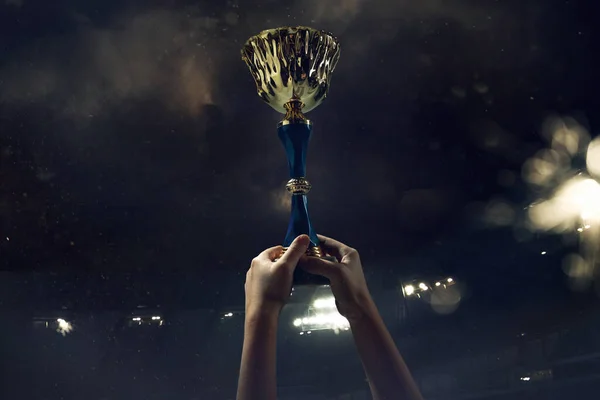 Prix de la victoire, mains masculines serrant la coupe des gagnants contre ciel sombre nuageux — Photo