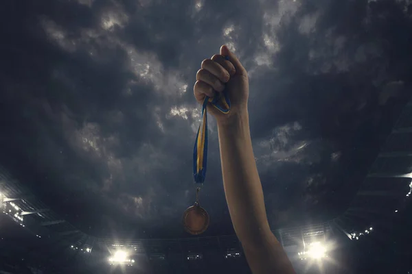 Награда за победу, мужские руки затягивают медаль победителей против облачного темного неба — стоковое фото