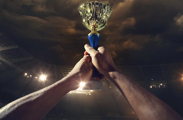 Award of victory, male hands tightening the cup of winners against cloudy dark sky — Stock Photo, Image