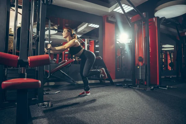 Joven mujer caucásica muscular practicando en gimnasio con equipo. Bienestar, estilo de vida saludable, culturismo. — Foto de Stock
