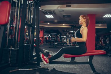 Genç kaslı beyaz kadın spor salonunda aletlerle pratik yapıyor. Sağlık, sağlıklı yaşam tarzı, vücut geliştirme..