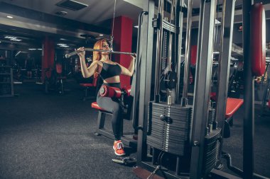 Genç kaslı beyaz kadın spor salonunda aletlerle pratik yapıyor. Sağlık, sağlıklı yaşam tarzı, vücut geliştirme..