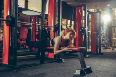 Genç kaslı beyaz kadın spor salonunda aletlerle pratik yapıyor. Sağlık, sağlıklı yaşam tarzı, vücut geliştirme..
