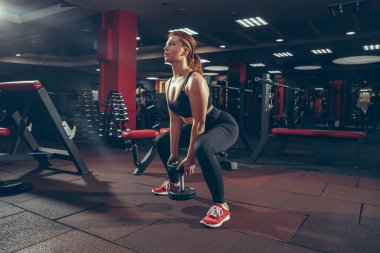 Genç kaslı beyaz kadın spor salonunda aletlerle pratik yapıyor. Sağlık, sağlıklı yaşam tarzı, vücut geliştirme..