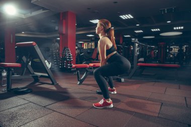 Genç kaslı beyaz kadın spor salonunda aletlerle pratik yapıyor. Sağlık, sağlıklı yaşam tarzı, vücut geliştirme..