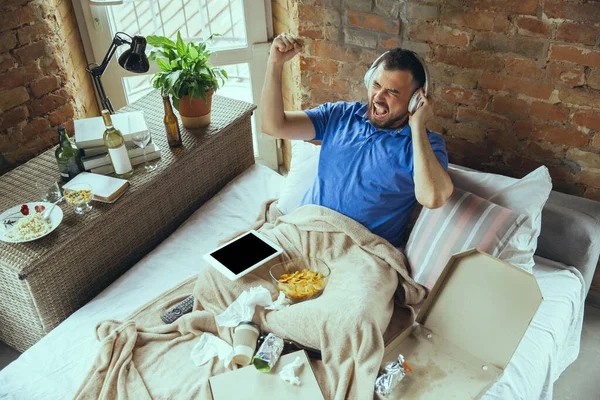 Lazy man living the whole life in his bed surrounded with messy