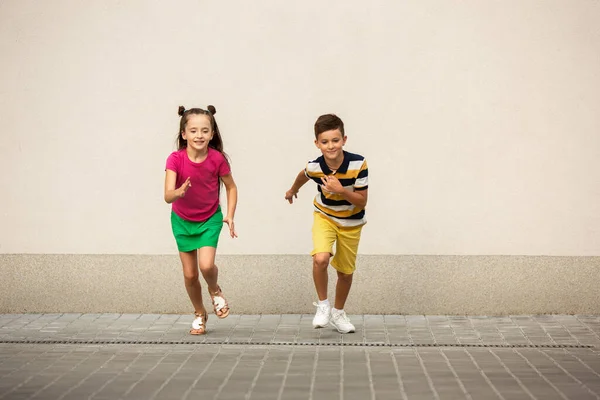 Deux enfants souriants, garçon et fille courant ensemble en ville, ville dans la journée d'été — Photo