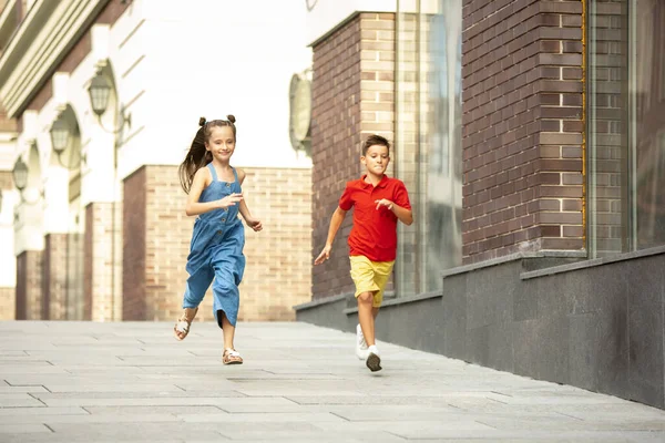 웃는 두 아이들, 소년 소녀들이 여름에 도시에서 함께 뛰고 있습니다 — 스톡 사진