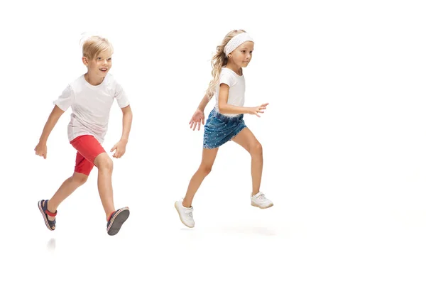 Ευτυχισμένο μικρό καυκάσιο κορίτσι και αγόρι πηδούν και τρέχουν απομονωμένοι σε λευκό φόντο — Φωτογραφία Αρχείου