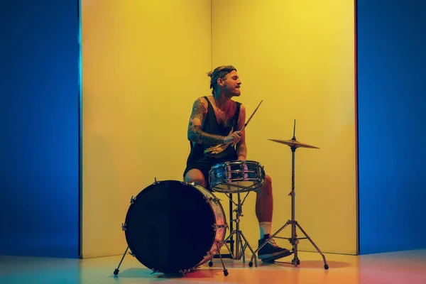 Jeune musicien caucasien inspiré performer sur fond jaune dans la lumière au néon — Photo