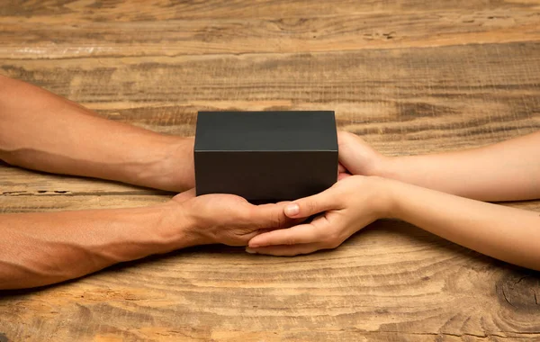 Humans hands holding a present, gift, surprise box isolated on wooden background — Stock Photo, Image