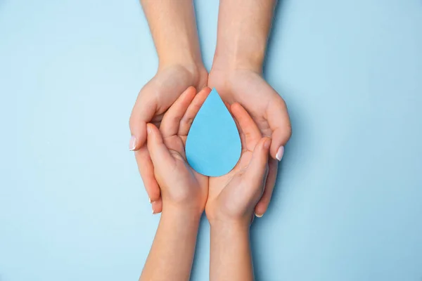 Human hands holding water drop isolated on white wooden background