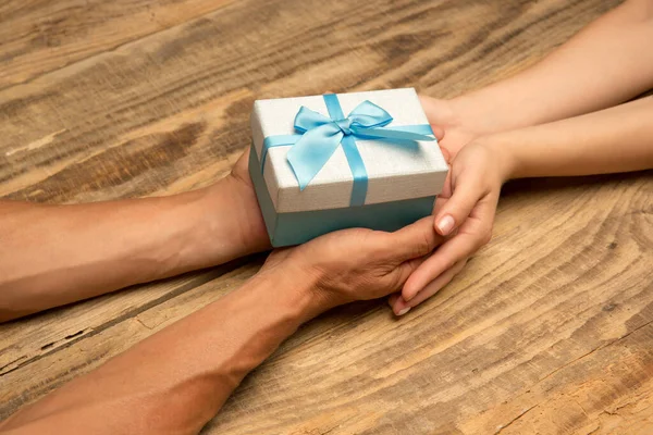 Manos humanas sosteniendo un regalo, regalo, caja sorpresa aislada sobre fondo de madera — Foto de Stock