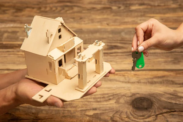 Концепція нерухомості та екології - крупним планом картина людських рук, що тримає будинок на дерев'яному тлі — стокове фото