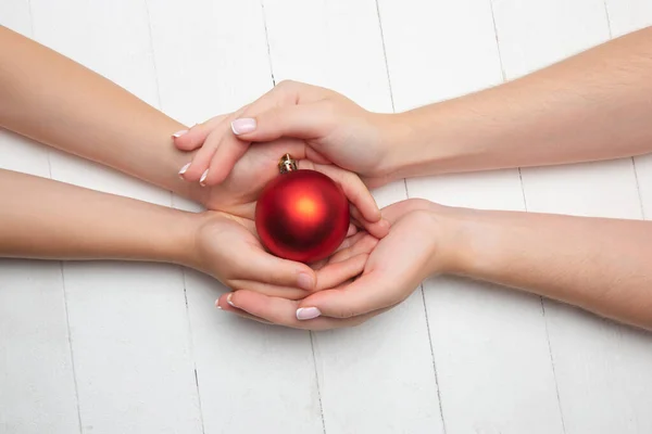 Humans hand holding a Christmas ball isolated on wooden white background — Stock Photo, Image