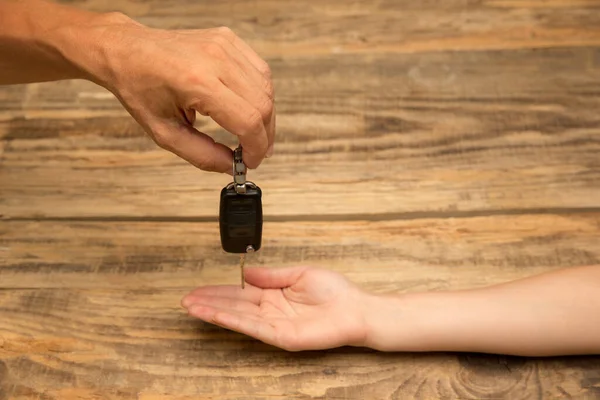 Руки людини тримають ключ автомобіля ізольований на дерев'яному фоні з копійкою — стокове фото