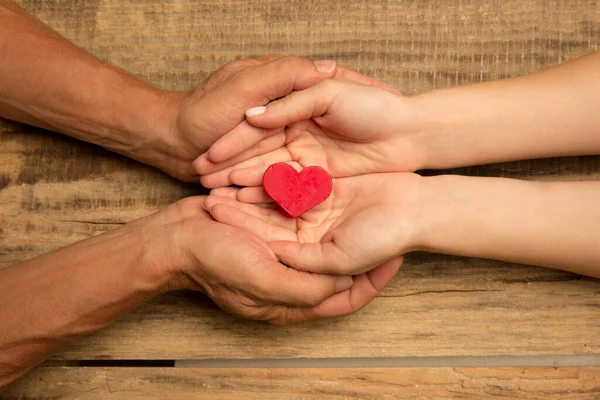 Manos humanas sosteniendo, dando corazón aislado sobre fondo de madera — Foto de Stock