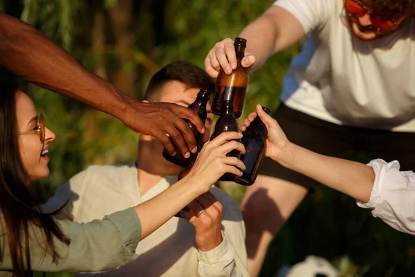 Grupo de amigos batendo copos de cerveja durante piquenique na praia. Estilo de vida, amizade, diversão, fim de semana e conceito de descanso . — Fotografia de Stock