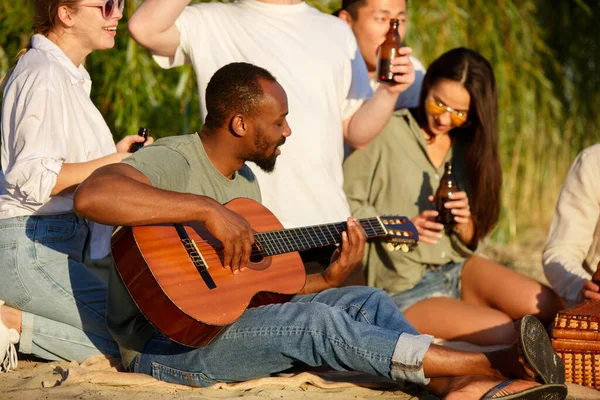 一群朋友在海滩野餐时碰碰啤酒杯.生活方式、友谊、享乐、周末和休息的概念. — 图库照片