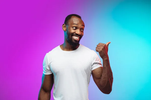 Afro-americano joven mans retrato en gradiente studio fondo en neón —  Fotos de Stock