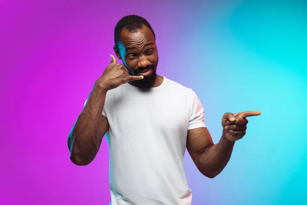 Afro-americano joven mans retrato en gradiente studio fondo en neón —  Fotos de Stock