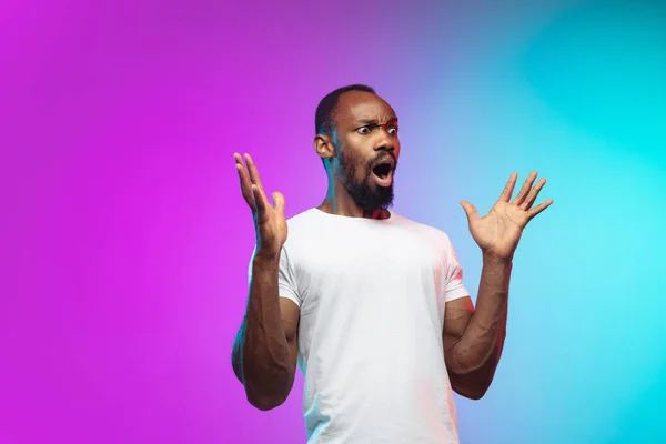 Afro-americano joven mans retrato en gradiente studio fondo en neón —  Fotos de Stock