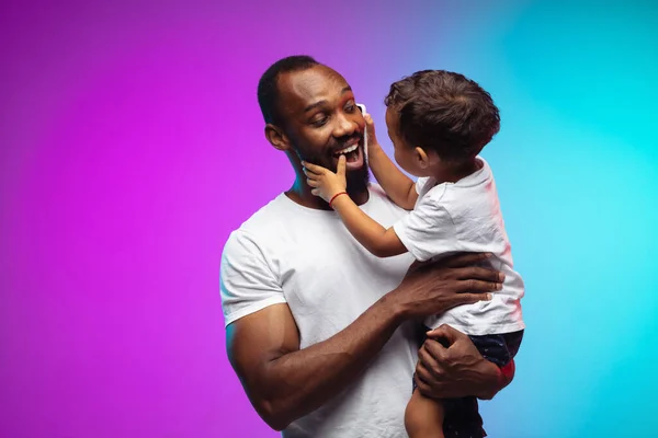 Afro-Amerikaanse vader en zoon portret op gradiënt studio achtergrond in neon — Stockfoto
