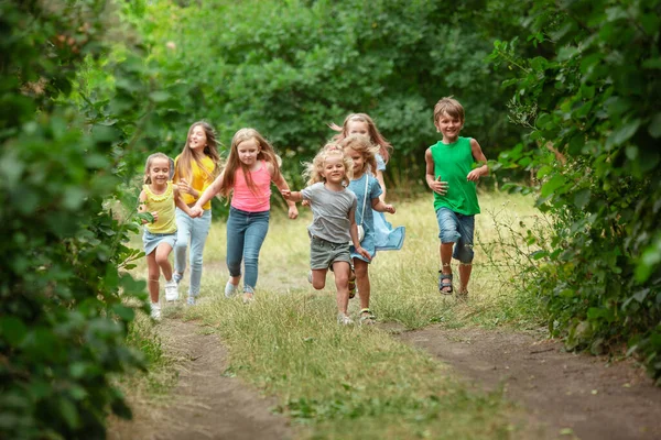 Niños, niños corriendo en el prado verde, bosque. Infancia y verano —  Fotos de Stock