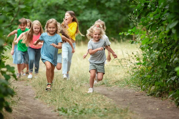 Дети, дети, бегущие по зеленому лугу, лесу. Детство и лето — стоковое фото