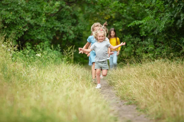 Niños, niños corriendo en el prado verde, bosque. Infancia y verano —  Fotos de Stock