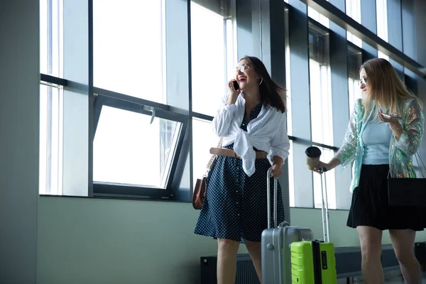 Mujeres jóvenes esperando la salida en el aeropuerto, viajero con equipaje pequeño, influencers estilo de vida — Foto de Stock