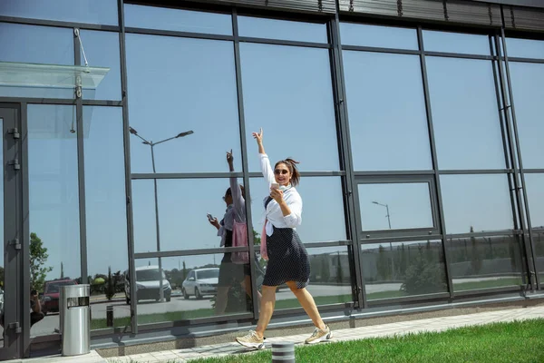 Giovane donna che cammina contro il muro di vetro in aeroporto, viaggiatore con piccoli bagagli, stile di vita influenzatori — Foto Stock