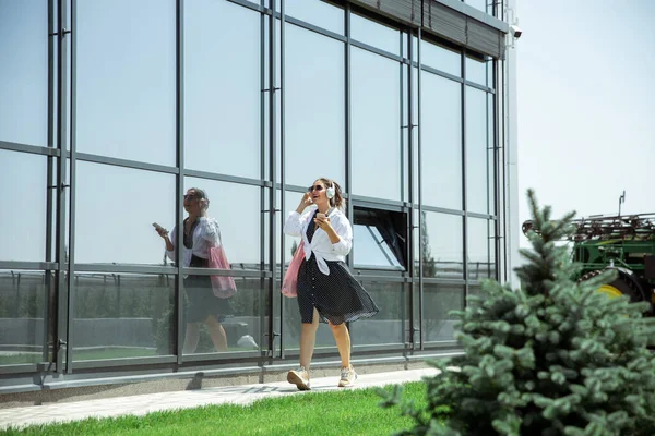 Młoda kobieta idąca pod szklaną ścianą na lotnisku, podróżnik z małym bagażem, stylem życia influencerów — Zdjęcie stockowe