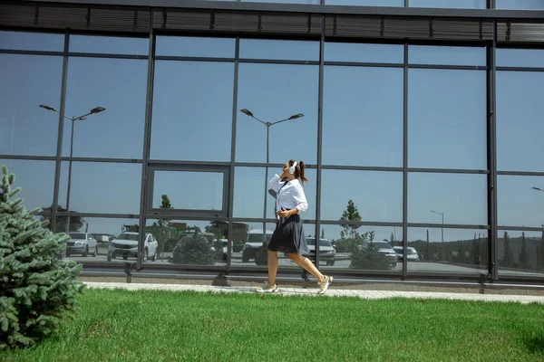 Giovane donna che cammina contro il muro di vetro in aeroporto, viaggiatore con piccoli bagagli, stile di vita influenzatori — Foto Stock