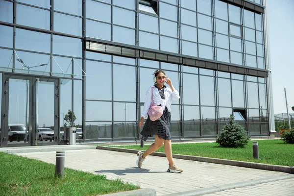 Giovane donna che cammina contro il muro di vetro in aeroporto, viaggiatore con piccoli bagagli, stile di vita influenzatori — Foto Stock