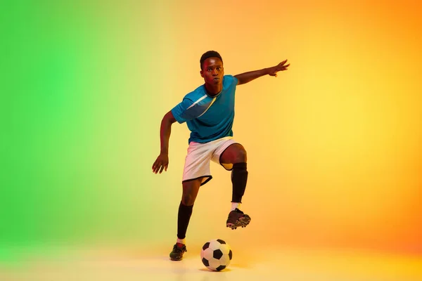 Football masculin, entraînement de footballeur en action isolé sur fond de studio dégradé au néon — Photo