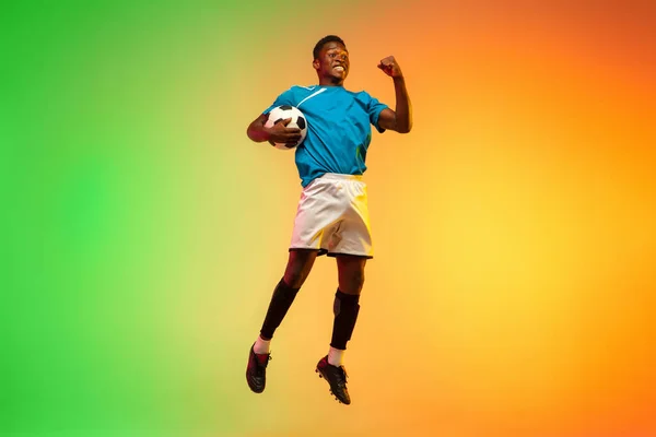 Calcio maschile, allenamento giocatore di calcio in azione isolato su sfondo studio gradiente in luce al neon — Foto Stock