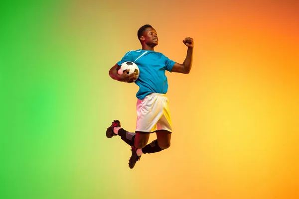 Calcio maschile, allenamento giocatore di calcio in azione isolato su sfondo studio gradiente in luce al neon — Foto Stock