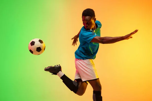 Calcio maschile, allenamento giocatore di calcio in azione isolato su sfondo studio gradiente in luce al neon — Foto Stock