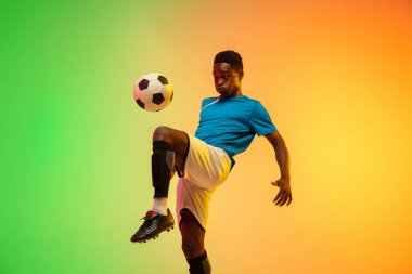Erkek futbol, hareket halinde futbol antrenmanı neon ışıklı arka planda izole edilmiş.