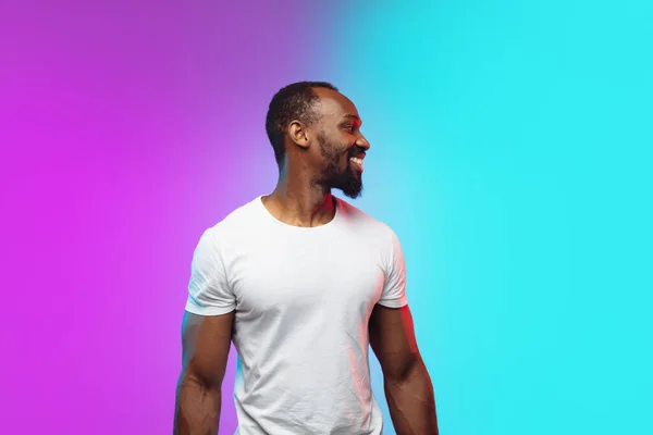 Afro-americano joven mans retrato en gradiente studio fondo en neón —  Fotos de Stock