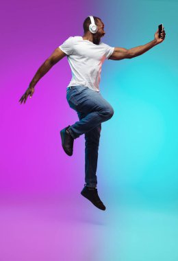 Afro-Amerikalı gençler, Neon 'daki gradyan stüdyo arka planında, yüksek atlama