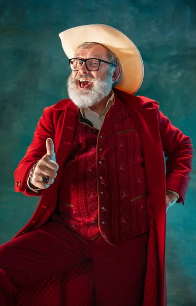 Moderno y elegante Santa Claus en traje rojo de moda y sombrero de vaqueros sobre fondo oscuro — Foto de Stock