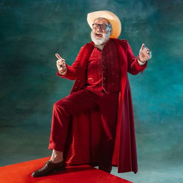 Moderno Papai Noel elegante em terno elegante vermelho e chapéu de cowboys no fundo escuro — Fotografia de Stock