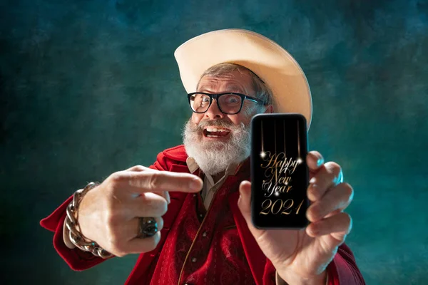 Moderno Papai Noel elegante em terno elegante vermelho e chapéu de cowboys no fundo escuro — Fotografia de Stock